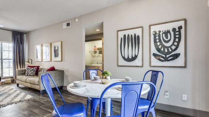 a living room with blue chairs and a table at The Hyde Park at Valley Ranch