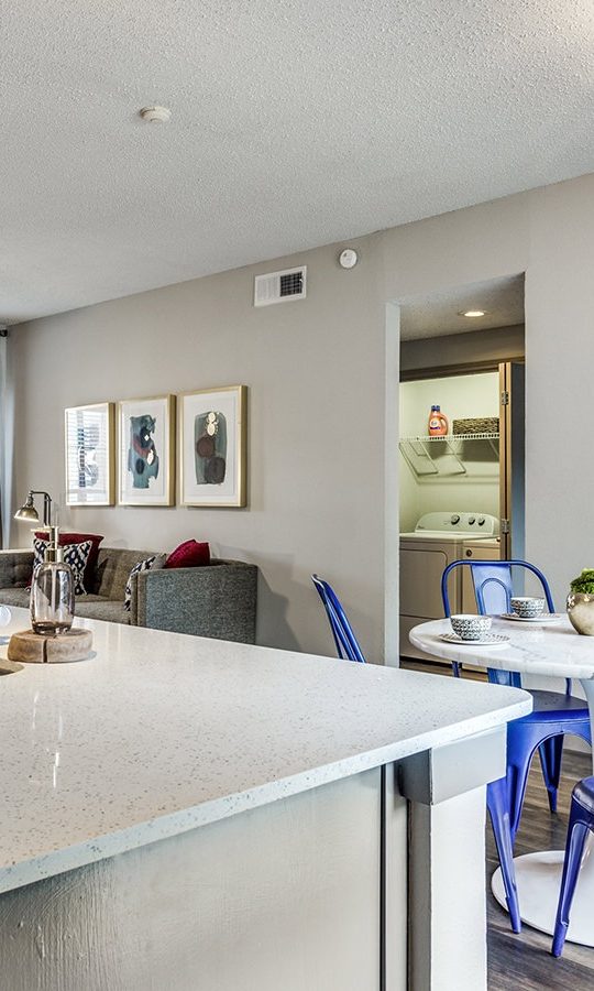 a kitchen with a sink, counter top and blue chairs at The Hyde Park at Valley Ranch