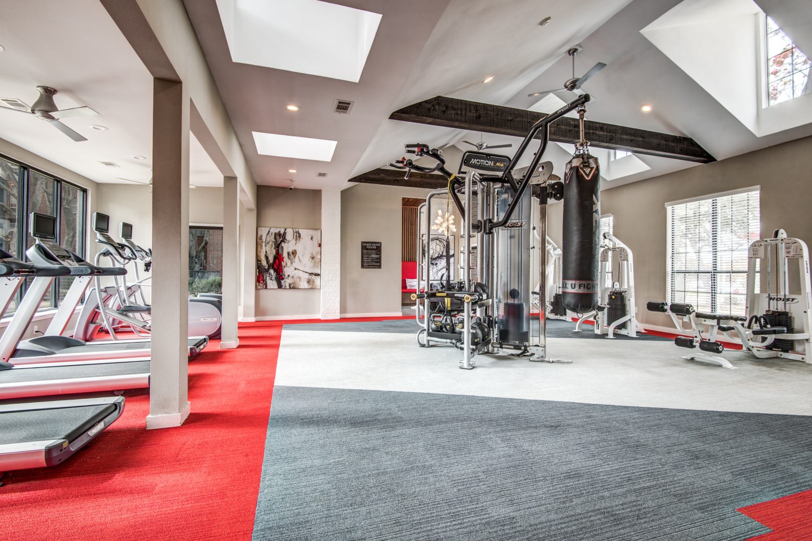 a gym room with tread machines and red carpet at The Hyde Park at Valley Ranch