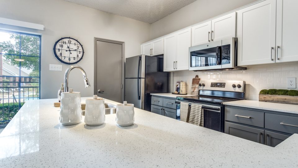 a kitchen with white cabinets and a clock on the wall at The Hyde Park at Valley Ranch